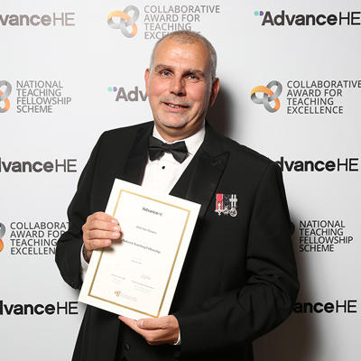 Ian Davies in a tuxedo holding a certificate