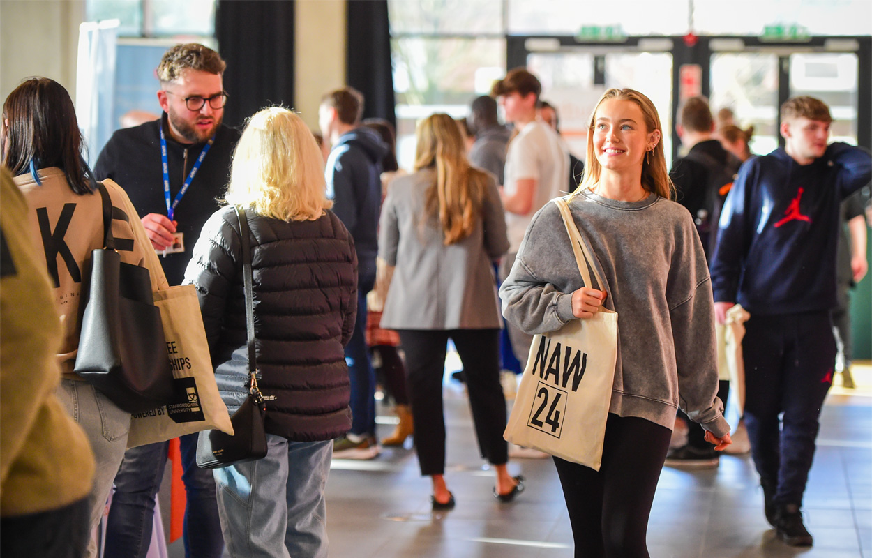 A female apprentice visitor is carrying a goodie bag and exploring the National Apprenticeship Week event