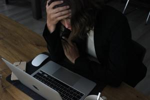 A woman sat a computer looking stressed