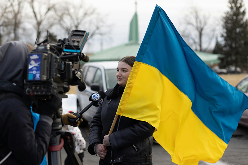 A television crew interviewing a women holding the Ukraine flag