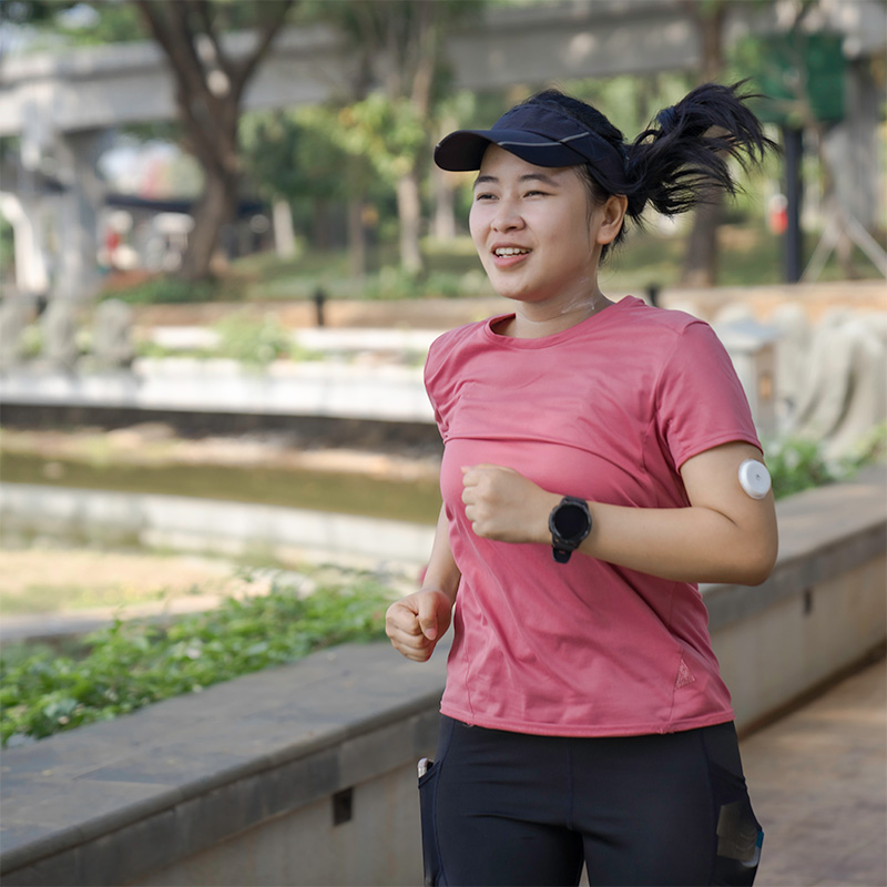 A diabetic woman running outside with a glucose monitor on her arm