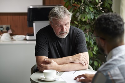 Elderly man in meeting situation with another man.