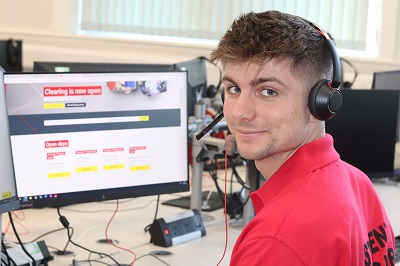 man with headset sat in front of a computer