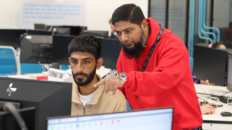 Two men are collaborating on a computer in a modern pc lab