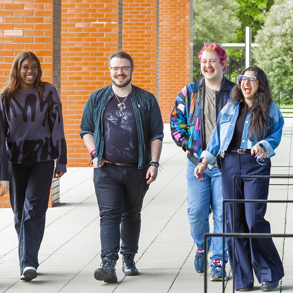 A diverse group of students casually dressed are chatting whilst walking outside the Catalyst building