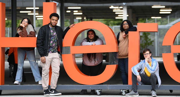 A group of casually dressed students are based outside the London campus posing for a photo