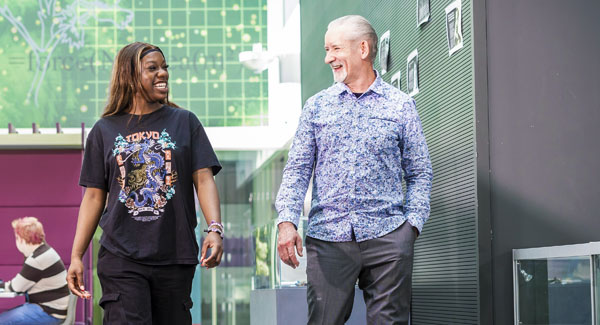 A female and male student are chatting whilst walking in the modern open space in the Science Centre